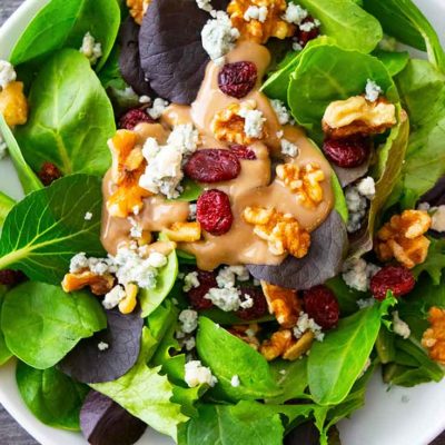 An overhead view looking down into a white bowl filled with this Cranberry Walnut Salad.