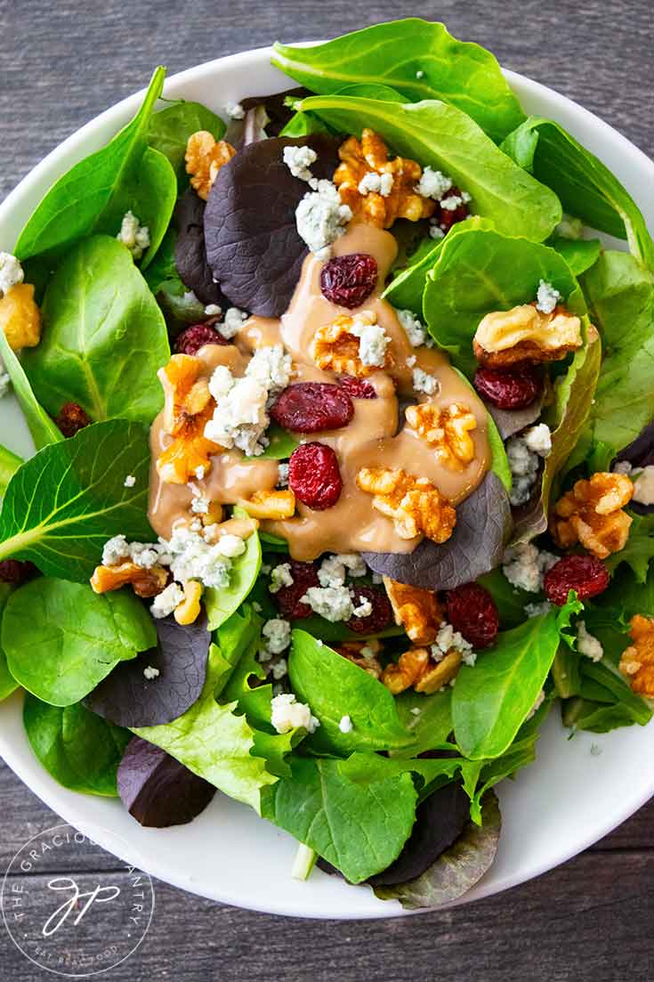 An overhead view looking down into a white bowl filled with this Cranberry Walnut Salad.