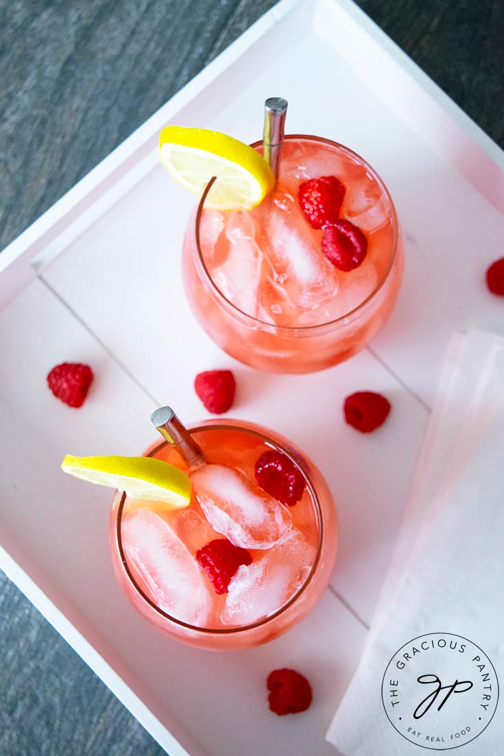 And overhead view of two glasses of raspberry lemonade sitting in a white serving tray.