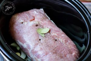 Step two of this Slow Cooker Pork Loin Recipe shows the pork loin and all spices in the slow cooker.