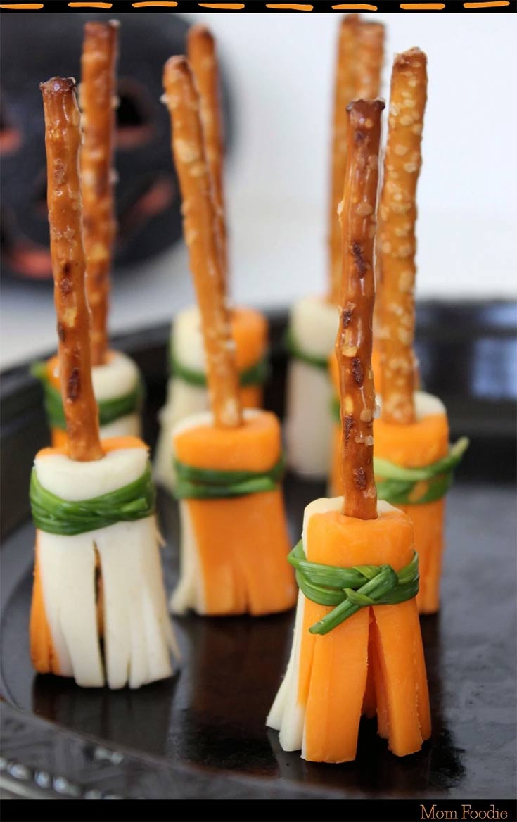 Pretzel and cheese broomsticks, standing on end on a serving platter.