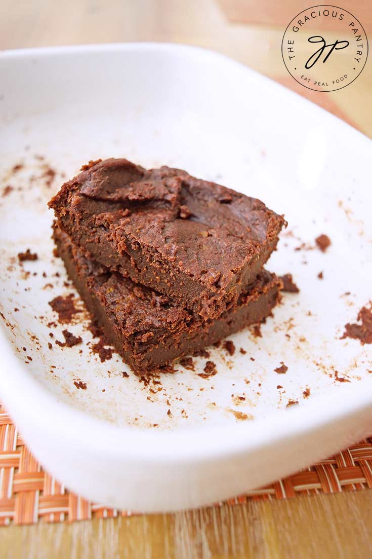 Two of these Flourless Brownies sit stacked in their baking dish.