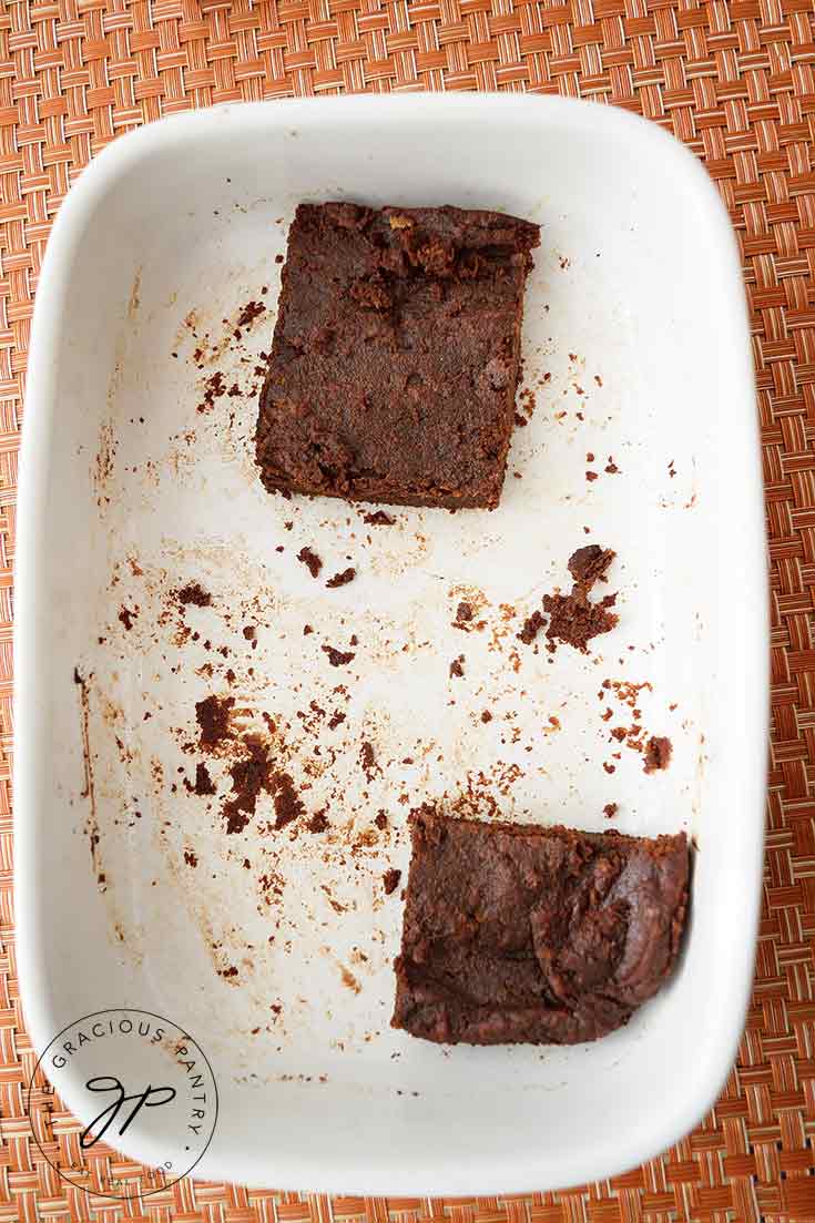 Two Flourless Brownies sit in their original spots in their baking dish, the only two remaining brownies.
