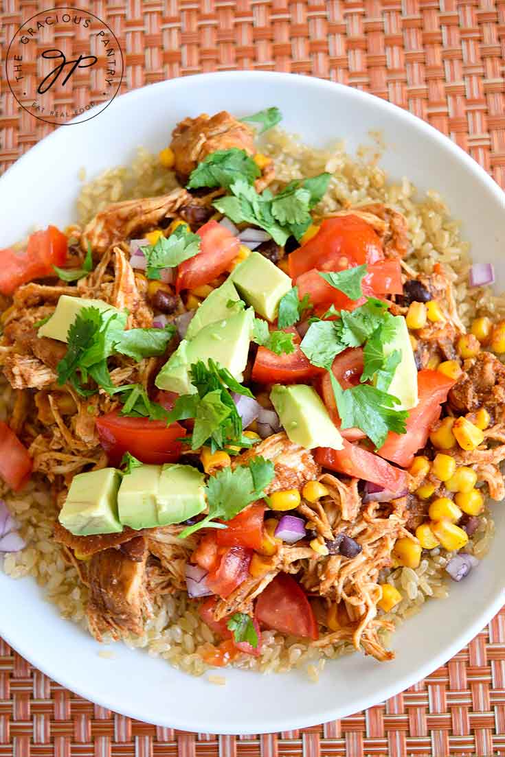 An overhead view of this Instant Pot Mexican Chicken shows a delicious view of mostly the garnishings with little bits of chicken and brown rice showing around the edges.