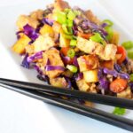 A side view of this Japanese Tempeh Skillet shows the tempeh , carrots, purple cabbage and green onions if bright, vibrant colors against a white plate.
