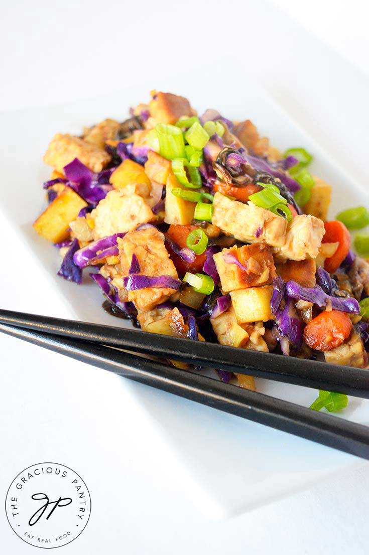 A side view of this Japanese Tempeh Skillet shows the tempeh , carrots, purple cabbage and green onions if bright, vibrant colors against a white plate.