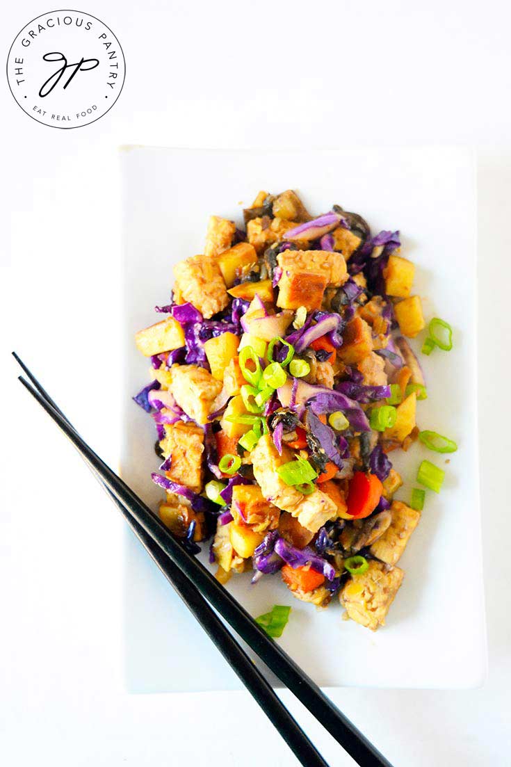 This Japanese Tempeh Skillet sits on a white, rectangular plate with black chopsticks placed across it diagonally.