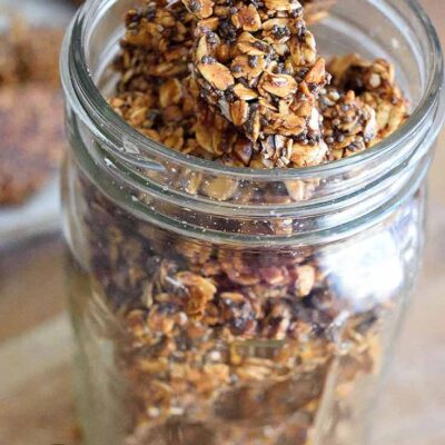 A canning jar sits filled with this Pumpkin Spice Granola Bark. The lid is off so you can see the bark inside the jar from the top as well as the sides.