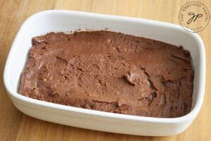 Step two of this Flourless Brownies Recipe is to smooth the thick batter evenly into a 6 by 9 inch casserole or baking dish after greasing the pan.