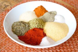 Individual spices sit next to each other in a bowl, just prior to mixing.