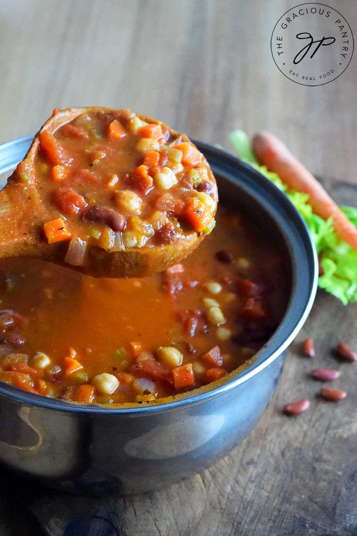 A pot with a full ladle just off the stove, filled with Minestrone Soup. Hot and delicious and ready to enjoy.