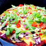 A black skillet sits with this Vegan Pizza Dough and finished toppings.