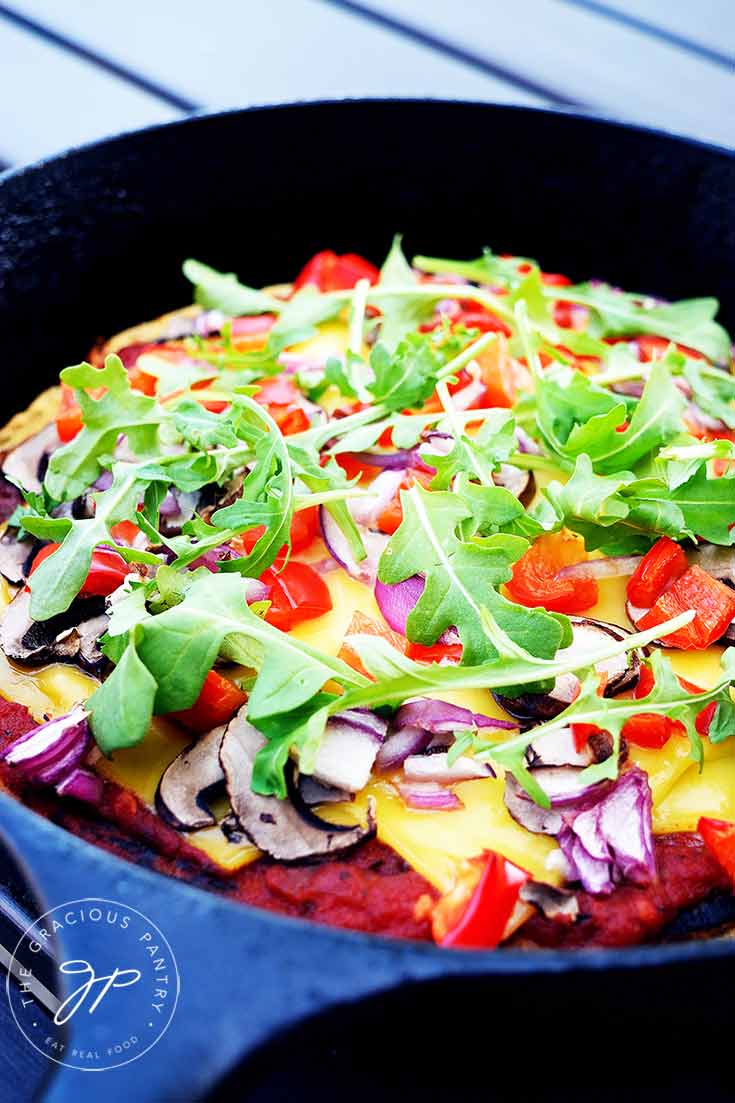 A black skillet sits with this Vegan Pizza Dough and finished toppings.