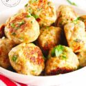 A white bowl filled with ground turkey meatballs sits on a white table, ready to serve.