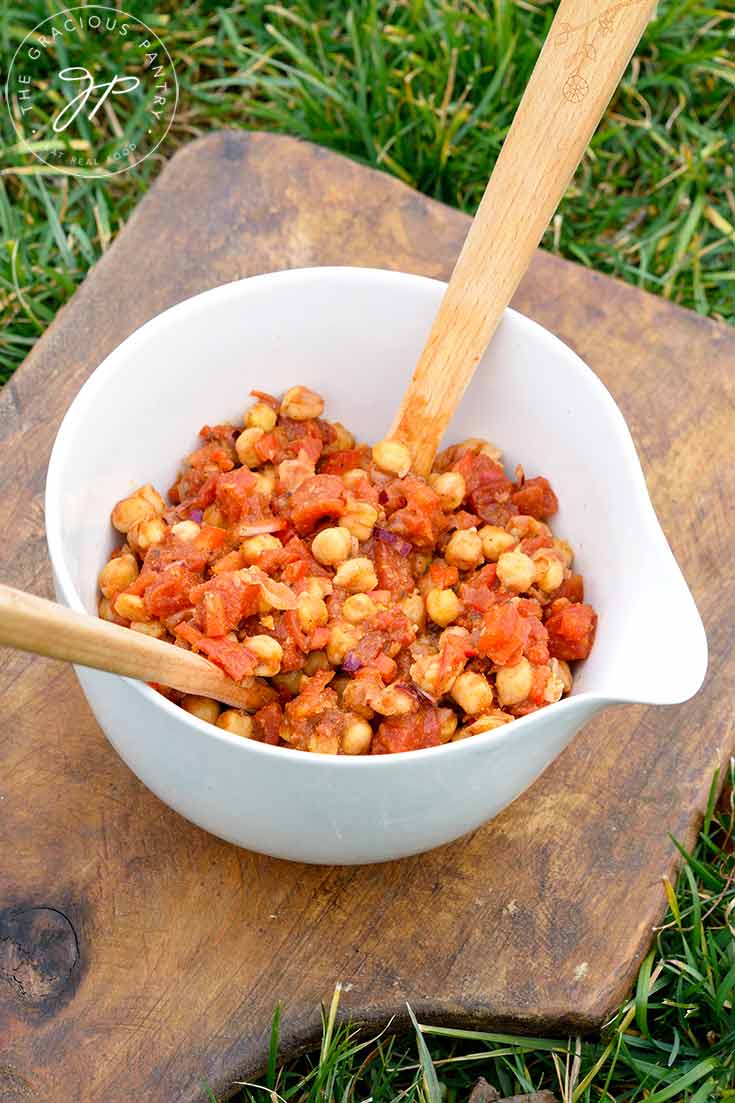 A further back view of this Indian Chickpea Salad shows two wooden serving spoons in the bean salad, ready to serve up a dish of this deliciousness.