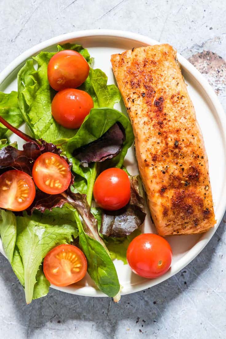 Air Fryer Salmon on a white plate with a green salad.