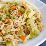 A white bowl filled with this Egg Roll In A Bowl Recipe sits on a slate tabletop. You can see bits of chicken, cabbage, shredded carrots and sliced green onions.