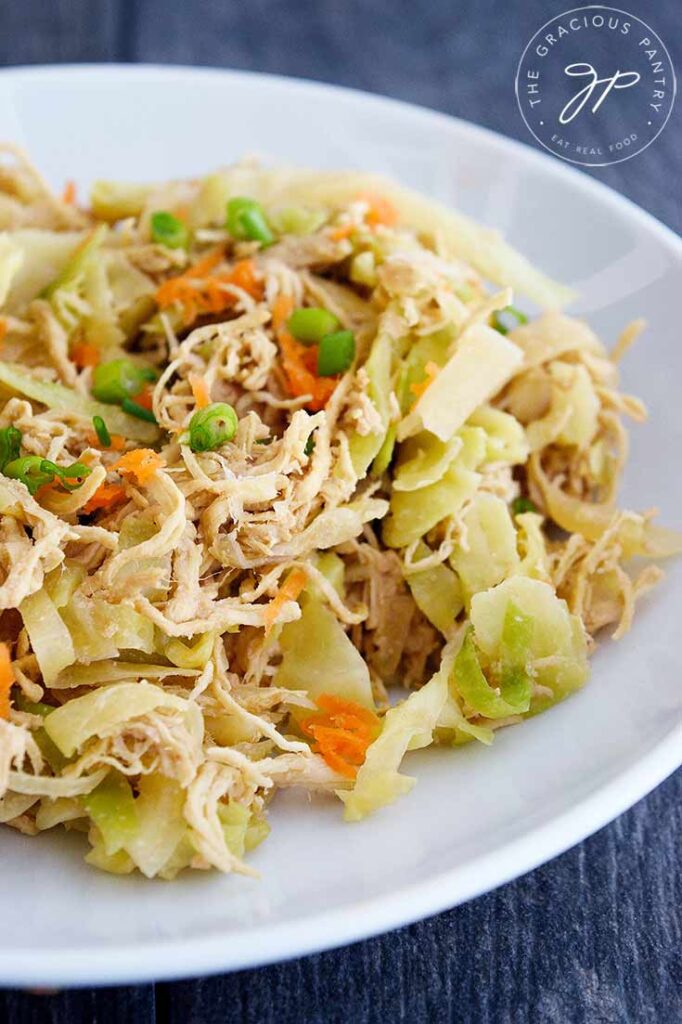 A white bowl filled with this Egg Roll In A Bowl Recipe sits on a slate tabletop. You can see bits of chicken, cabbage, shredded carrots and sliced green onions.