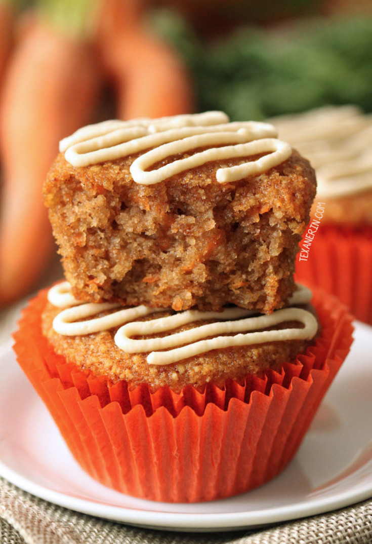 A close up of two healthier carrot cake muffins stacked on top of each other. A bite has been taken from the muffin on top.