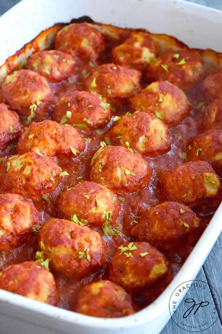 A white casserole dish sits filled with just-out-of-the-oven Italian Meatballs.