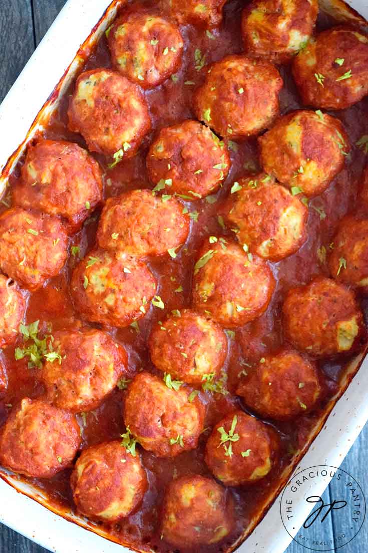 An overhead view looking down into a white casserole dish filled with this freshly made Italian Meatballs.