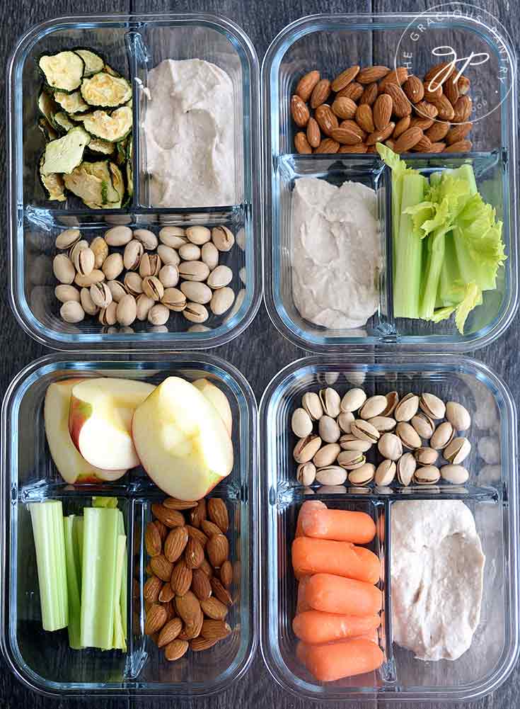 Four meal prep containers all filled with different snack combinations.