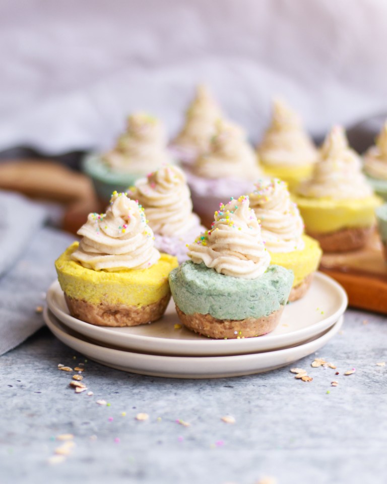 Four No Bake Mini Vegan Cheesecakes on a plate, with more on a cutting board in the background.