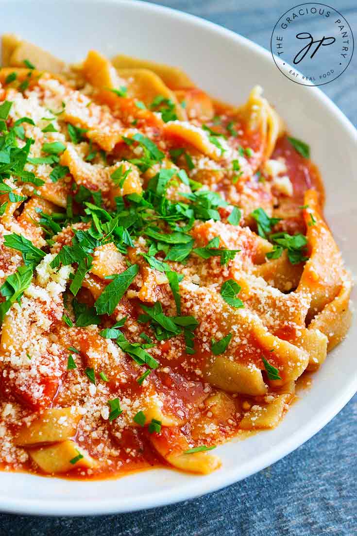 A beautiful bowl of fresh, homemade pasta sits garnished with parmesan and fresh parsley in this guide to How To Make Homemade Pasta.