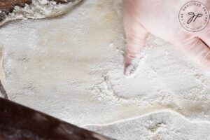 Flour your work surface well, roll out the dough and sprinkle with more flour.