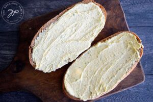 Spread the butter over both halves of the loaf of bread.