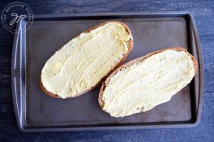 Place the buttered loaf on a baking sheet and bake.