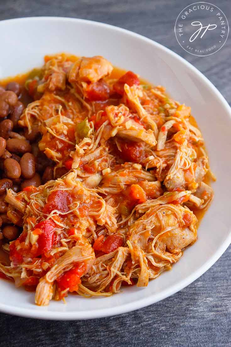 Looking down into a bowl filled with chicken ropa vieja and a side of pinto beans.