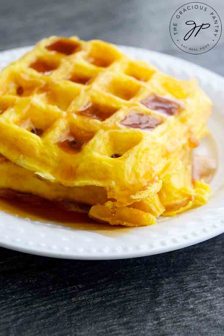 Golden Egg Waffles with maple syrup drizzled over the top.