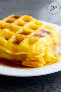 Bright, golden yellow egg waffles sit on a table, ready to serve and eat.
