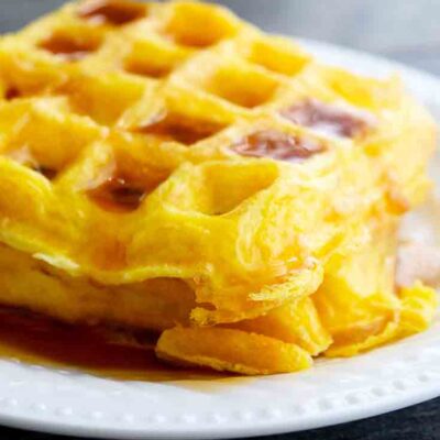 Bright, golden yellow egg waffles sit on a table, ready to serve and eat.