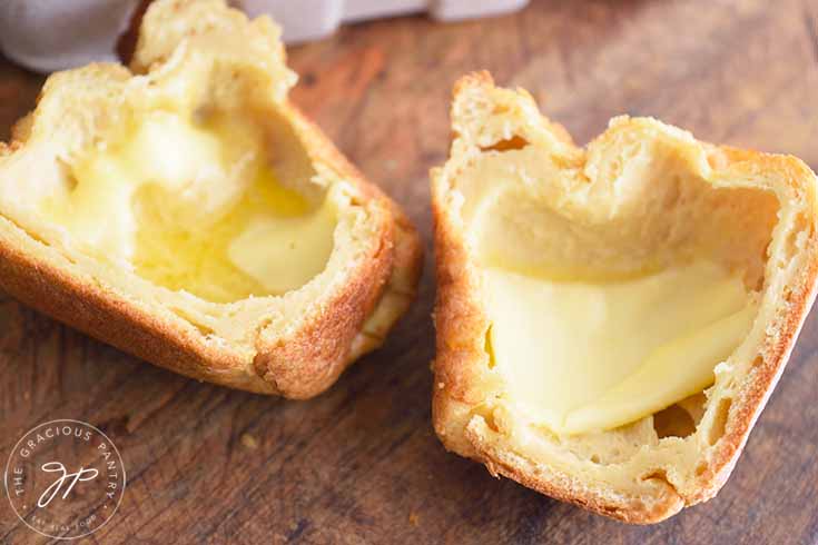 A popover sits cut in half with butter melting into it's middle.