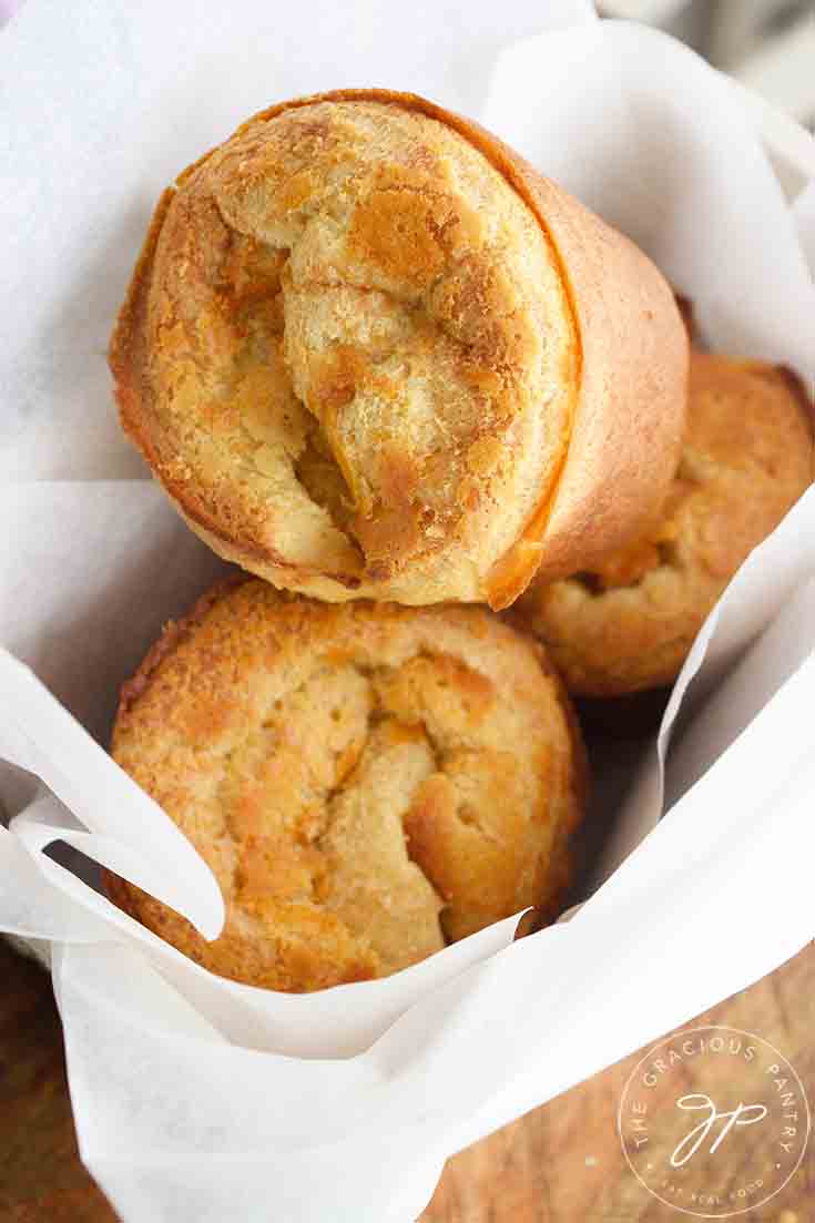 Three warm popovers in a small bread basket, ready to eat.