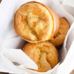 An overhead view of this popover recipe shows three popovers in a parchment lined bread basket.