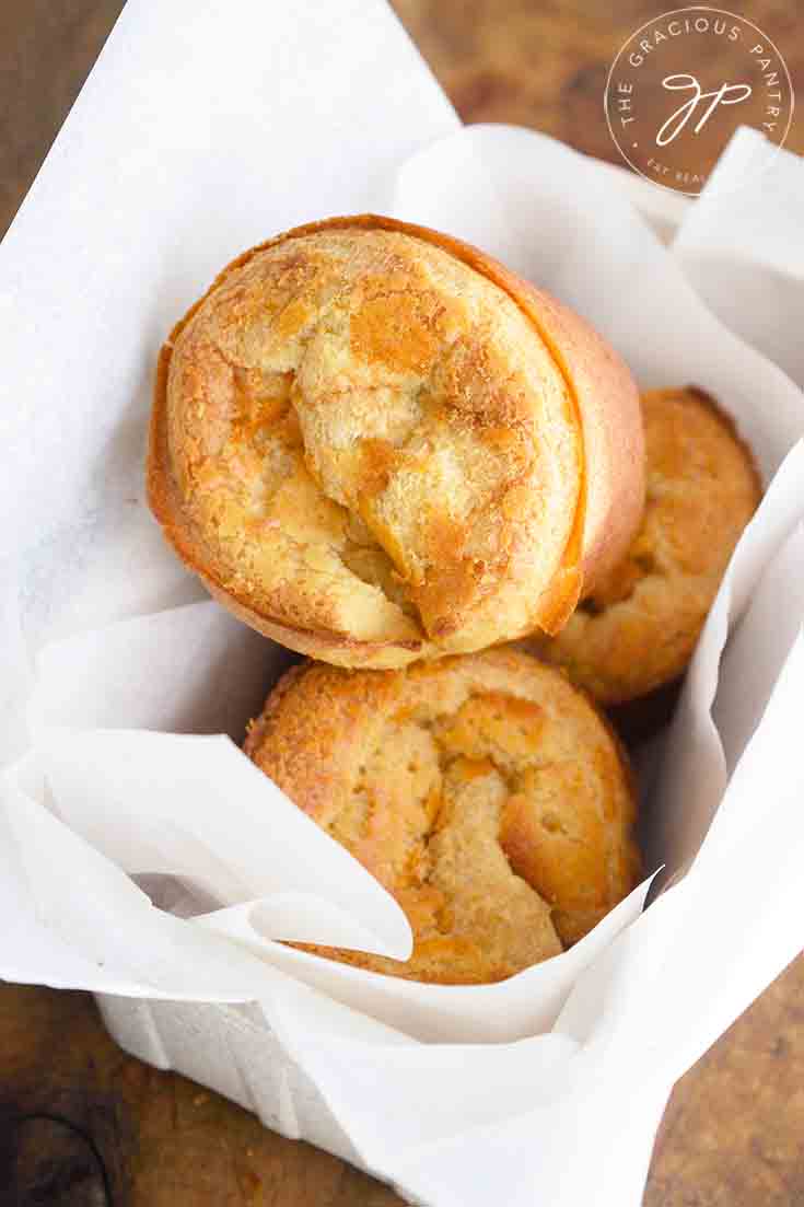 An overhead view of this popover recipe shows three popovers in a parchment lined bread basket.