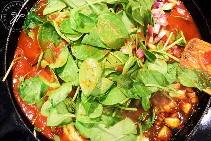 Adding fresh spinach to the sauce.