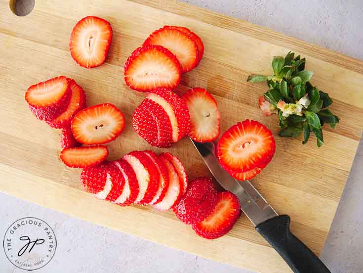 Sliced strawberries on a cutting board.
