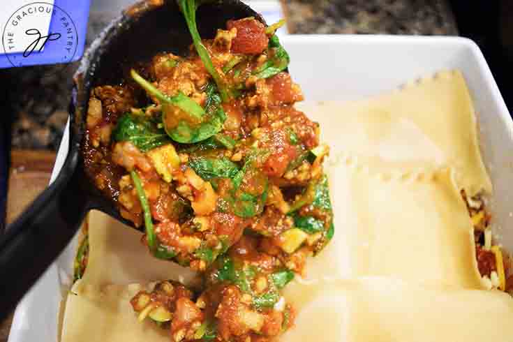 Adding meat filling over lasagna noodles.