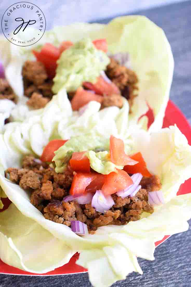 Cabbage leaf tacos sitting, ready to eat, on a red serving plate.