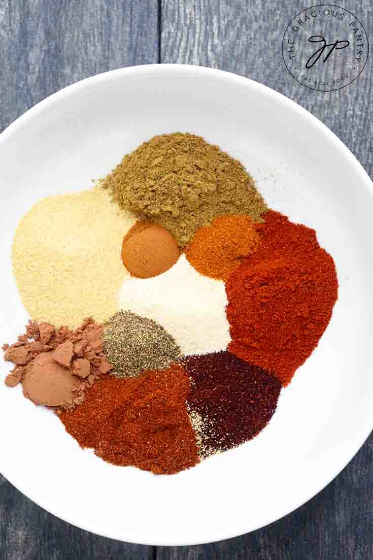 All the spices for this Chili Seasoning Recipe sit in a white bowl, waiting to be blended together. You can see each individual spice.