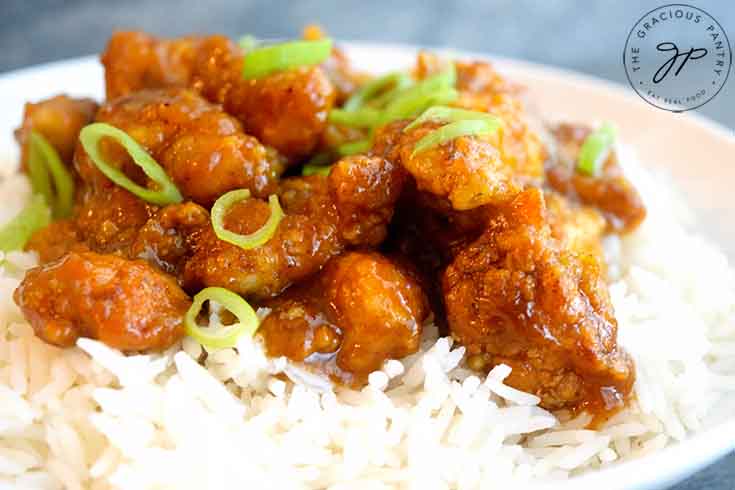 A horizontal shot of a bowl filled with Easy Orange Chicken.