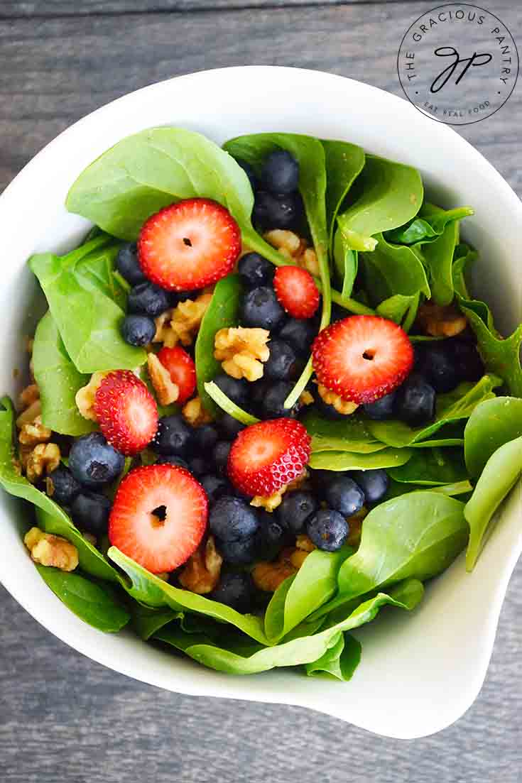 An overhead view looking down into a large, white bowl filled wit this spinach salad recipe.