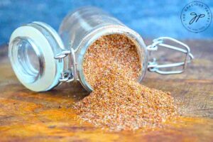 Chili Spice in an open jar, tipped over onto a wooden surface.