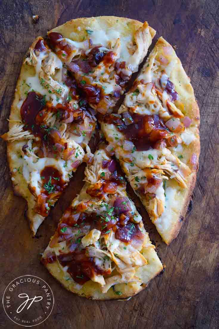 A freshly cut Naan Pizza still on the cutting board.