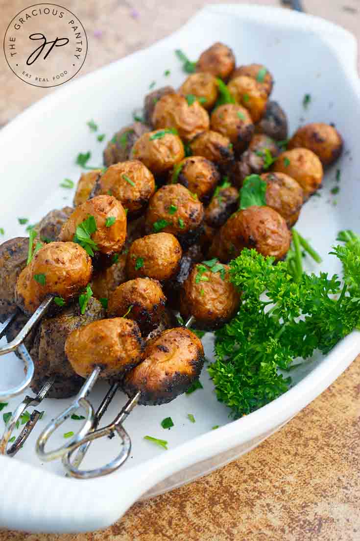 A serving plate filled with Grilled Potato Skewers and topped with fresh parsley.