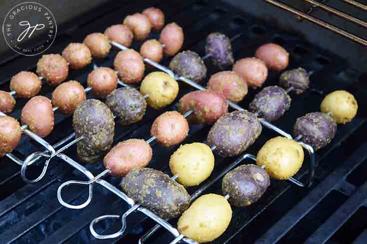 The potatoes on their skewers and skewer rack, roasting on the barbecue.